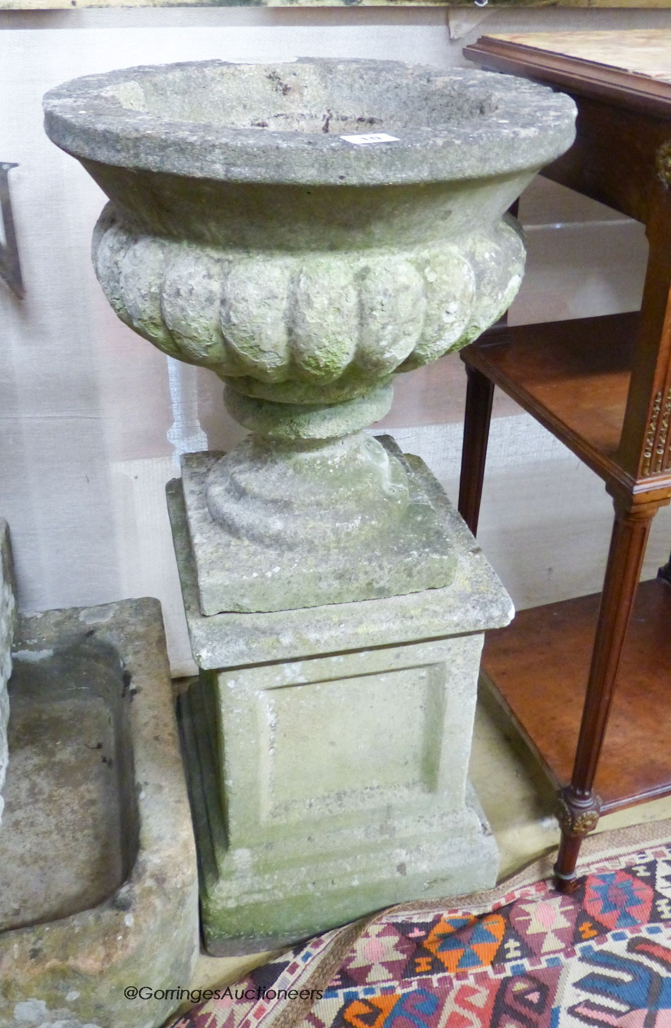 A reconstituted stone campana garden urn on plinth, 40cm diameter, 82cm high